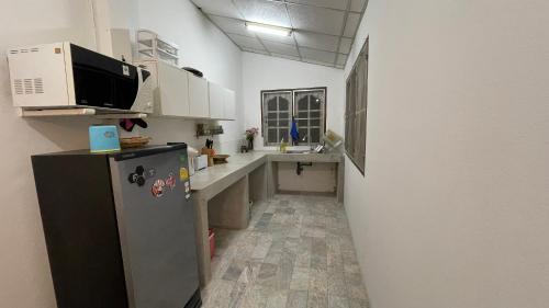 a small kitchen with a refrigerator and a microwave at บ้านเพื่อน @อุทัยธานี in Ban Don Khwang