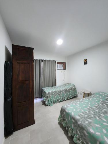 a hotel room with two beds and a dresser at Apartamento com varanda Reserva do Sahy in Mangaratiba