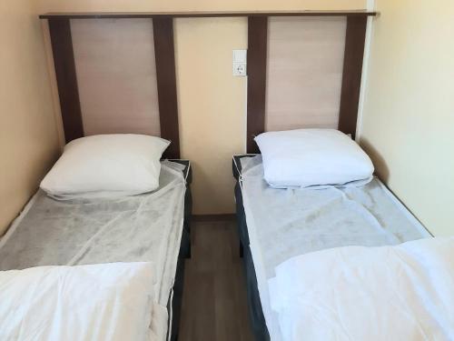 duas camas num quarto com lençóis brancos em Mobil-Home Caves, 3 pièces, 4 personnes - FR-1-783-28 em Caves