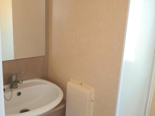 uma casa de banho com um lavatório branco e um espelho. em Mobil-Home Caves, 3 pièces, 4 personnes - FR-1-783-28 em Caves