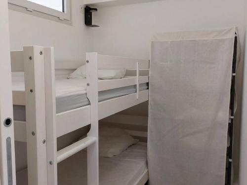 Ce lit se trouve dans un dortoir doté de 2 lits superposés blancs et d'une fenêtre. dans l'établissement Studio Cabine Rénové Proche Plage, Commerces, Clim, WIFI, Parking - FR-1-328-230, à La Grande Motte