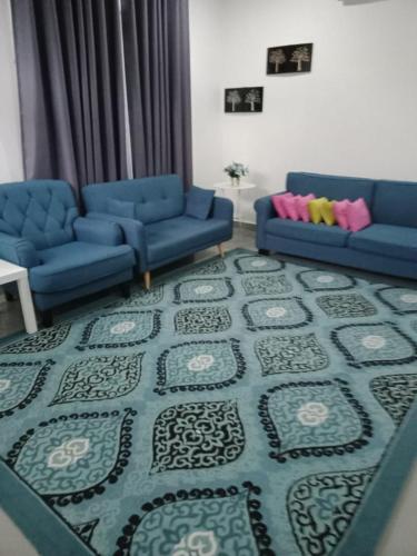 una sala de estar con 2 sofás azules y una alfombra en Inapsinggah homestay, en Kota Bharu