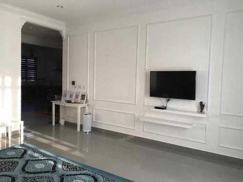 sala de estar blanca con TV de pantalla plana en Inapsinggah homestay, en Kota Bharu