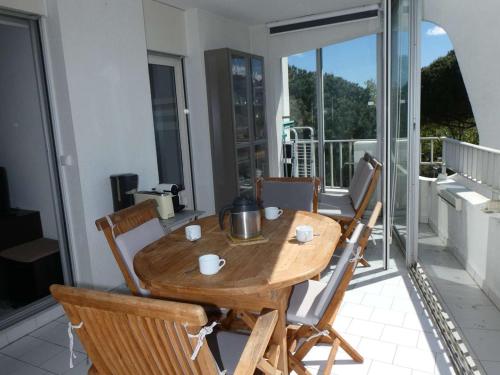 une table et des chaises en bois sur un balcon dans l'établissement Studio cabine avec piscine, climatisation, garage, à 300m plage - FR-1-328-259, à La Grande Motte