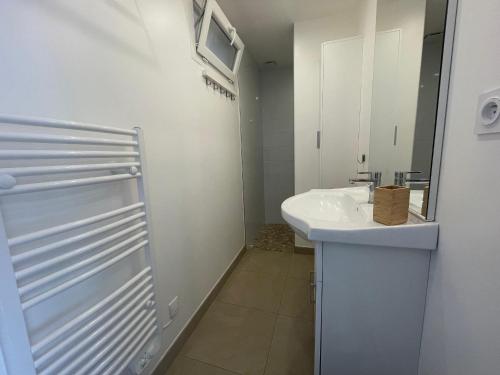 La salle de bains blanche est pourvue d'un lavabo et d'un miroir. dans l'établissement Appartement Banyuls-sur-Mer, 3 pièces, 4 personnes - FR-1-309-445, à Banyuls-sur-Mer