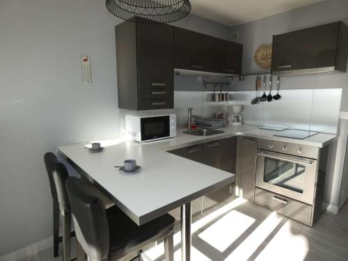 une cuisine avec une table avec des chaises et un micro-ondes dans l'établissement Studio Cabine Moderne, 100m de la Plage, Parking et Wifi Inclus - FR-1-328-253, à La Grande Motte