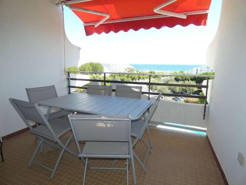 une table et des chaises sur un balcon avec un parasol dans l'établissement Appartement 3 pièces cabine avec piscine, vue mer, proche plage - FR-1-328-248, à La Grande Motte