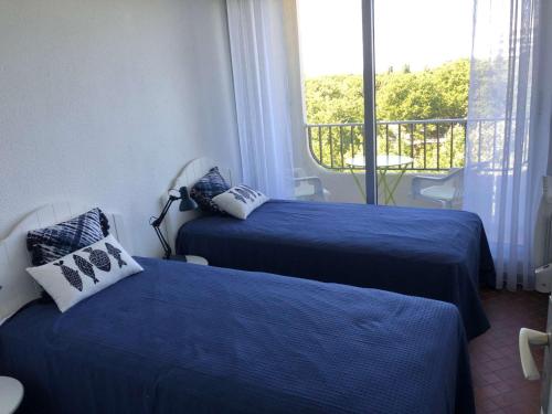 Cette chambre dispose de 2 lits bleus et d'un balcon. dans l'établissement Appartement 3 pièces cabine avec piscine, vue mer, proche plage - FR-1-328-248, à La Grande Motte