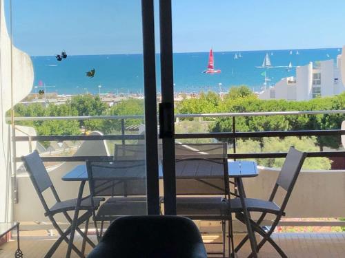 d'un balcon avec des tables et des chaises et une vue sur l'océan. dans l'établissement Appartement 3 pièces cabine avec piscine, vue mer, proche plage - FR-1-328-248, à La Grande Motte