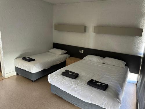 two beds in a room with two bags on them at Overlander Hotel in Mount Isa