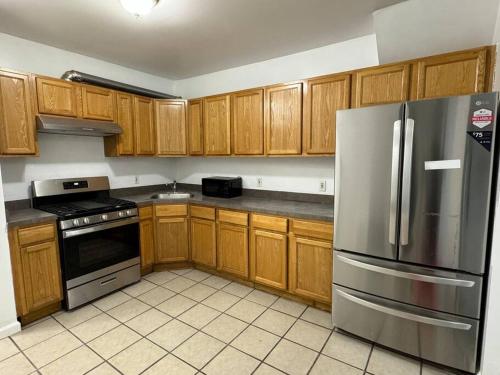 una cucina con armadi in legno e frigorifero in acciaio inossidabile di Comfy Family Home -Adjacent To NYC: 15 Guests a Passaic
