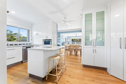 a kitchen with white cabinets and a island with bar stools at 198 Mystery Bay Road, Mystery Bay in Mystery Bay