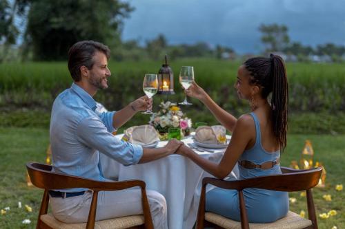 a man and woman sitting at a table with wine glasses at Gdas Bali Health and Wellness Resort - Adult Only in Ubud