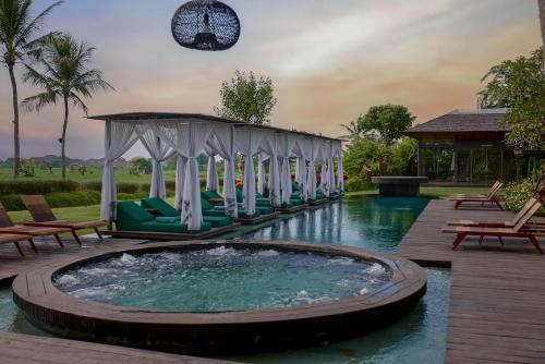 uma piscina com uma banheira de hidromassagem e cadeiras e um edifício em Gdas Bali Health and Wellness Resort em Ubud