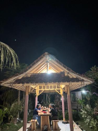 people sitting at a table in a pavilion at night at Sriwedari House Keramas in Gianyar