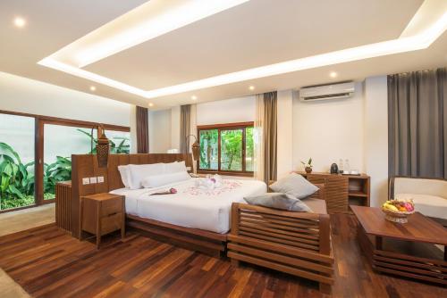 a bedroom with a large white bed and a table at Siemreap Vasinh Residence in Siem Reap