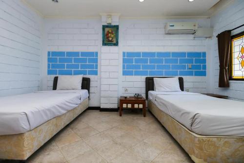 two beds in a room with blue and white walls at Ammara Legian By Vilarisi in Legian