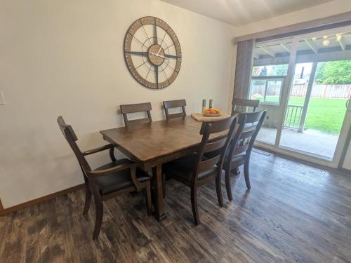 a dining room table with chairs and a clock on the wall at Cozy Place for Family and Friends in Dundee