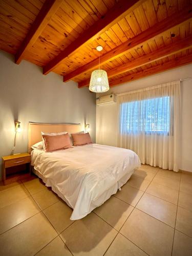 ein Schlafzimmer mit einem großen Bett und einer Holzdecke in der Unterkunft El Nido Bombal in Godoy Cruz