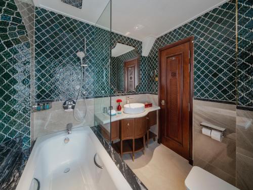 a bathroom with a tub and a sink at Peridot Gallery Classic Hotel in Hanoi