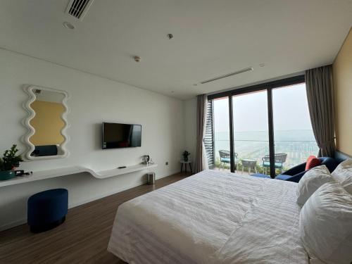 a bedroom with a bed and a tv and a window at Flamingo Ibiza Hải Tiến in Nam Khê