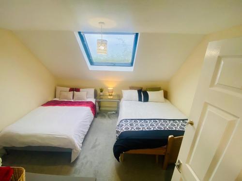 Duas camas num pequeno quarto com uma janela em Charming Entire 2-Bedroom House in Milton Keynes em Milton Keynes