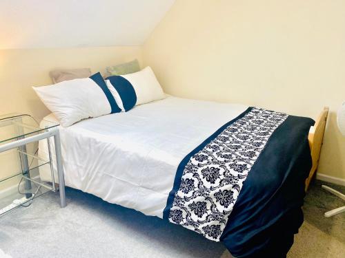 a bedroom with a bed with white and blue sheets at Charming Entire 2-Bedroom House in Milton Keynes in Milton Keynes