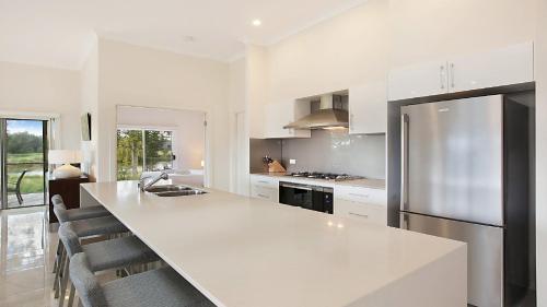 a kitchen with a large white counter and a refrigerator at Amber Lakes - The Vintage in Pokolbin