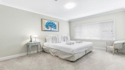 a white bedroom with a bed and a window at La Vita - The Vintage in Pokolbin