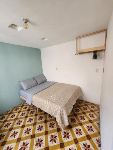 a small bedroom with a bed and a tiled floor at La Embajada Hostel in San Cristóbal de Las Casas