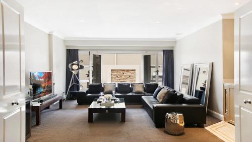 a living room with a black couch and a tv at The Vintage Manor in Pokolbin