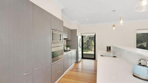 a kitchen with white cabinets and a sink and a microwave at Wine Down in Pokolbin