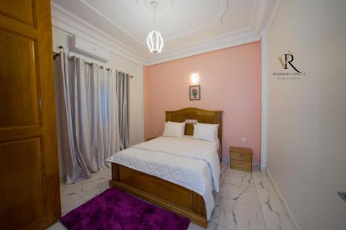 a bedroom with a bed and a purple rug at Résidence Vinelly in Douala