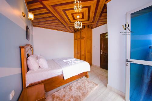 a bedroom with a bed with a wooden ceiling at Résidence Vinelly in Douala