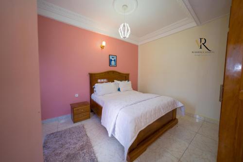 a bedroom with a bed and a pink wall at Résidence Vinelly in Douala