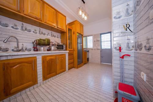 a large kitchen with wooden cabinets and a refrigerator at Résidence Vinelly in Douala