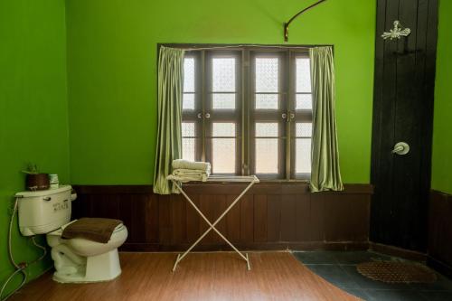 a green bathroom with a toilet and a window at Bee Friend Boutique Guesthouse in Chiang Mai