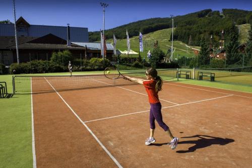 a young girl swinging a tennis racket on a tennis court at Štýlový Apartmán Andrea blízko Snowlandu Valča in Stará Turá