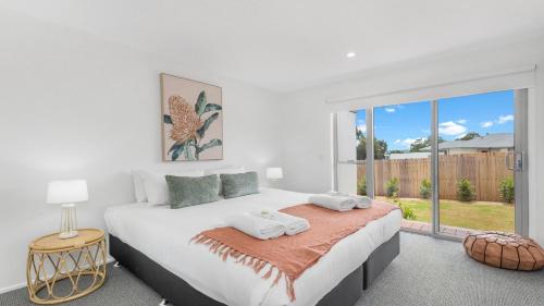 a white bedroom with a large bed and a window at Jacoru On 3 in Pokolbin