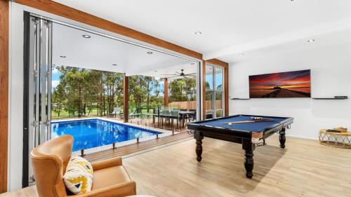 a pool table in a living room with a large window at Jacoru On 3 in Pokolbin