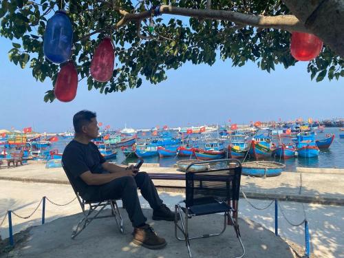 a man sitting in a chair in front of a harbor at Hoa Bien Motel in Ly Son