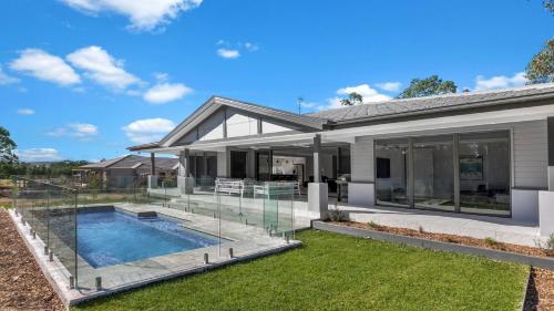 a house with a swimming pool and glass walls at The Residence in Pokolbin