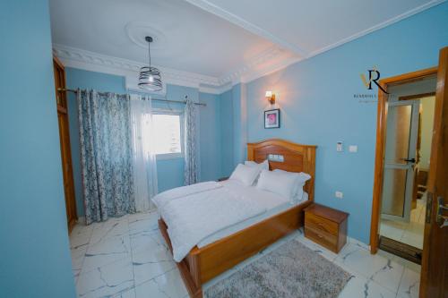a bedroom with a bed with blue walls and a window at Résidence Vinelly in Douala