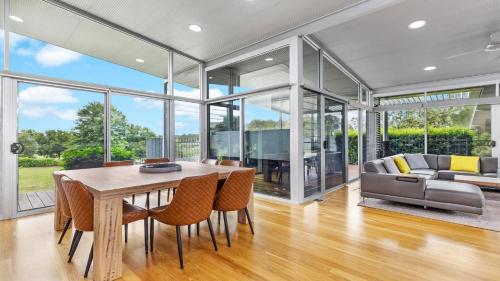 a dining room with a table and chairs and a couch at Olive Lakes in Pokolbin