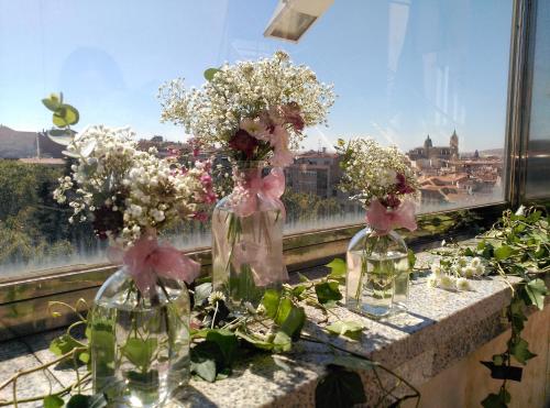 three glass vases filled with flowers on a ledge at Hotel Alameda Palace in Salamanca