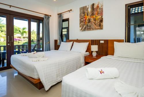 een slaapkamer met 2 bedden en een balkon bij Phatcharee Resort in Baan Tai