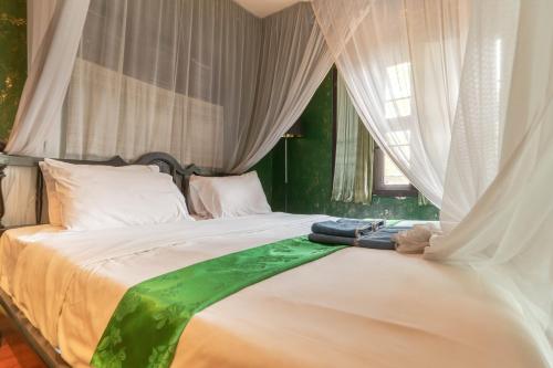 a bedroom with a large white bed with curtains at Bee Friend Boutique Guesthouse in Chiang Mai