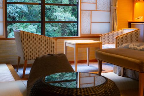 a living room with two chairs and a table at Tsuetate Onsen Hotel Hizenya in Oguni