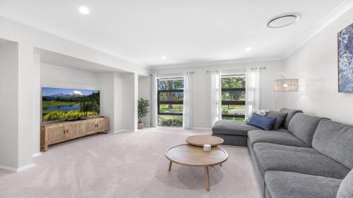 a living room with a couch and a tv at D'Vine Cottage in Pokolbin