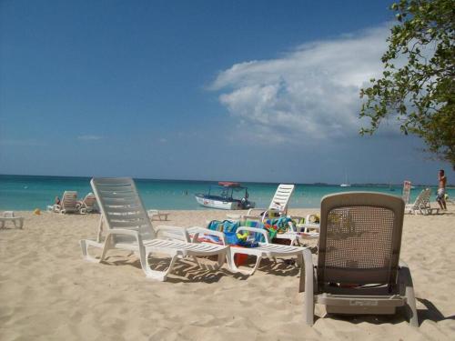 尼格瑞尔Studio Apt on 7 Mile Beach at Negril Beach Club的一群坐在海滩上的草坪椅